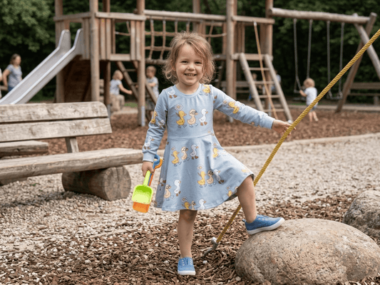 Mädchen trägt Kleid "Frühlingsbote" mit Enten und Gänseblümchen beim Spielen