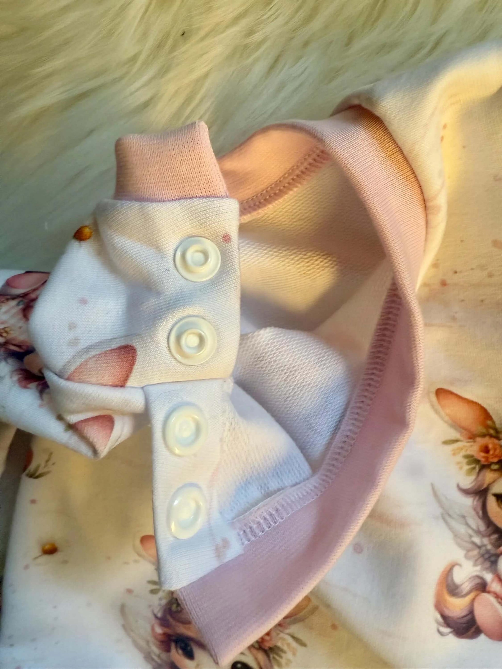Detailaufnahme des Einhornstoffmusters auf weißem Baby Pullover
