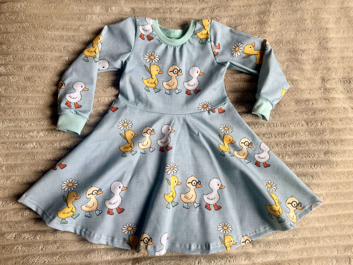 Kinderkleid grün-blau mit Entenmotiv, Frontansicht flach ausgelegt