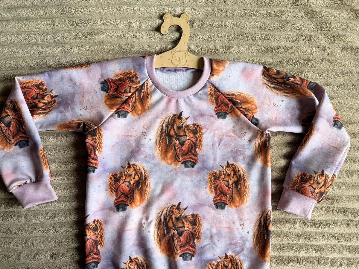 Nahaufnahme Herzenspferd-Motiv mit Mädchen und Pferd auf lila French Terry Pullover