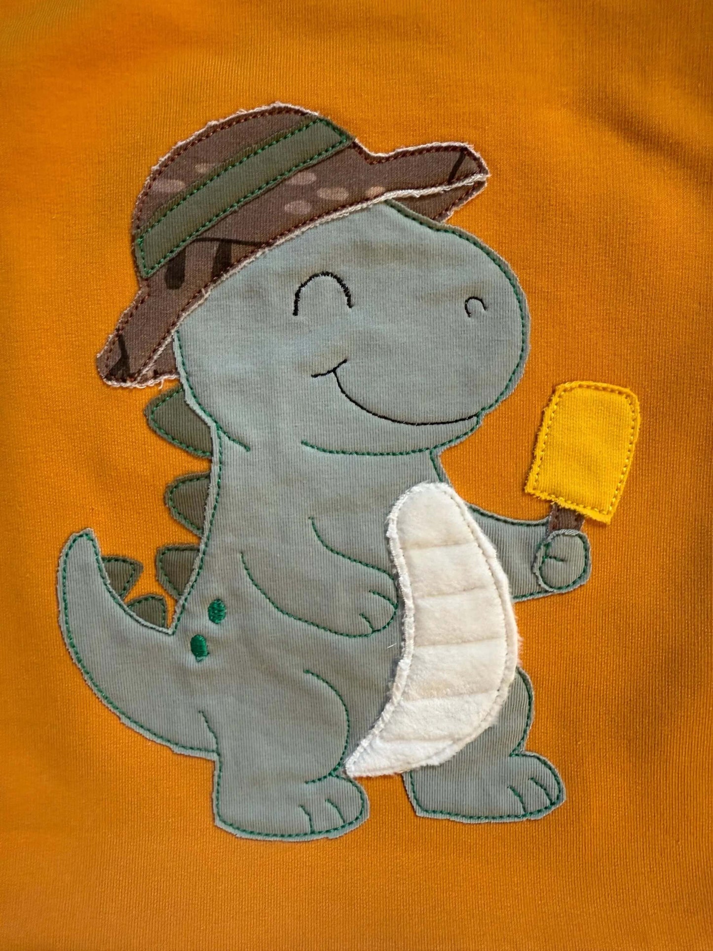 Detailaufnahme des Dino‑Stickbildes auf dem Shirt
