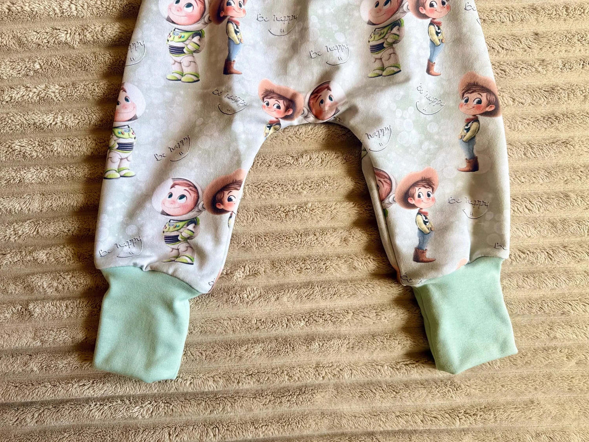 Nahaufnahme Astronaut und Cowboy Print „Be happy" mit grünem Beinbündchen an der Pumphose