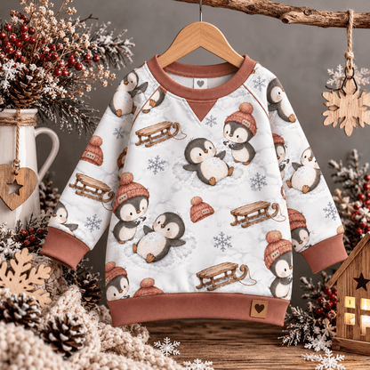 Schneeengel Pinguine vernäht zu Sweatshirt und Leggings Set, Kind trägt French Terry Pulli mit Pinguinen im Schnee Motiv, OEKO-TEX 100 Kinderstoff