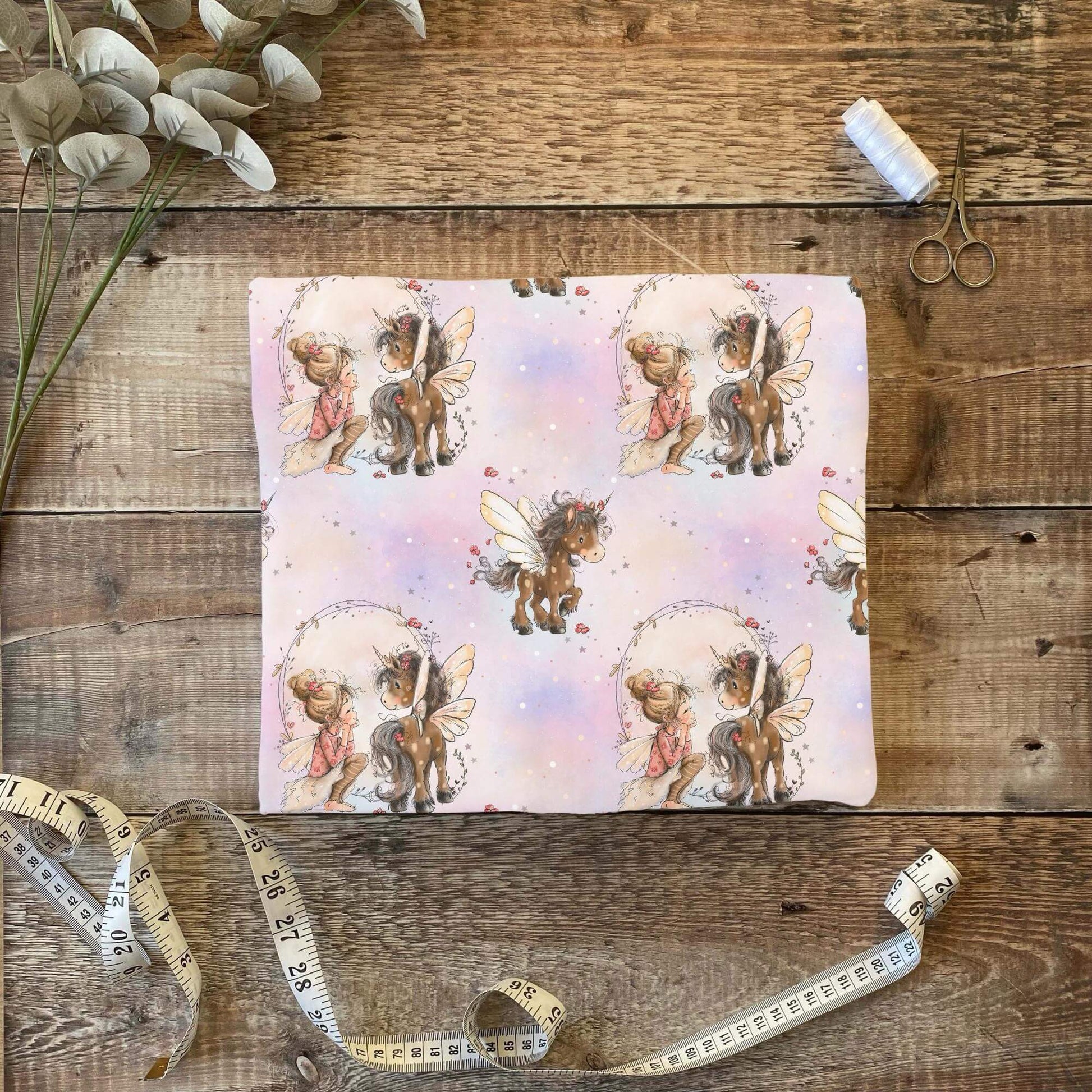 Babystoff Fee mit braunem Einhorn und sanften Aquarellfarben
