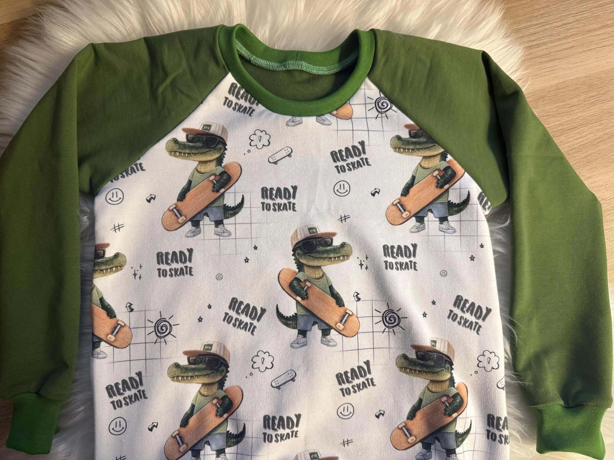 Nahaufnahme grünes Saumbündchen am Raglan Pullover für Kinder, Eigenproduktion Skater Kroko