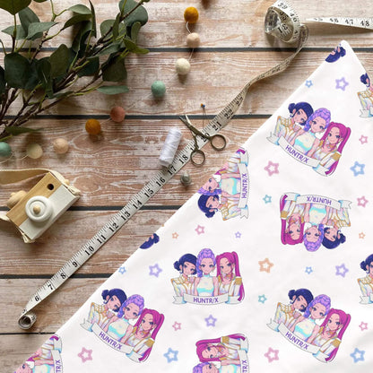 Stoff liegt dekorativ auf Holztisch mit Nähzubehör und zeigt das verspielte K Popband Design
