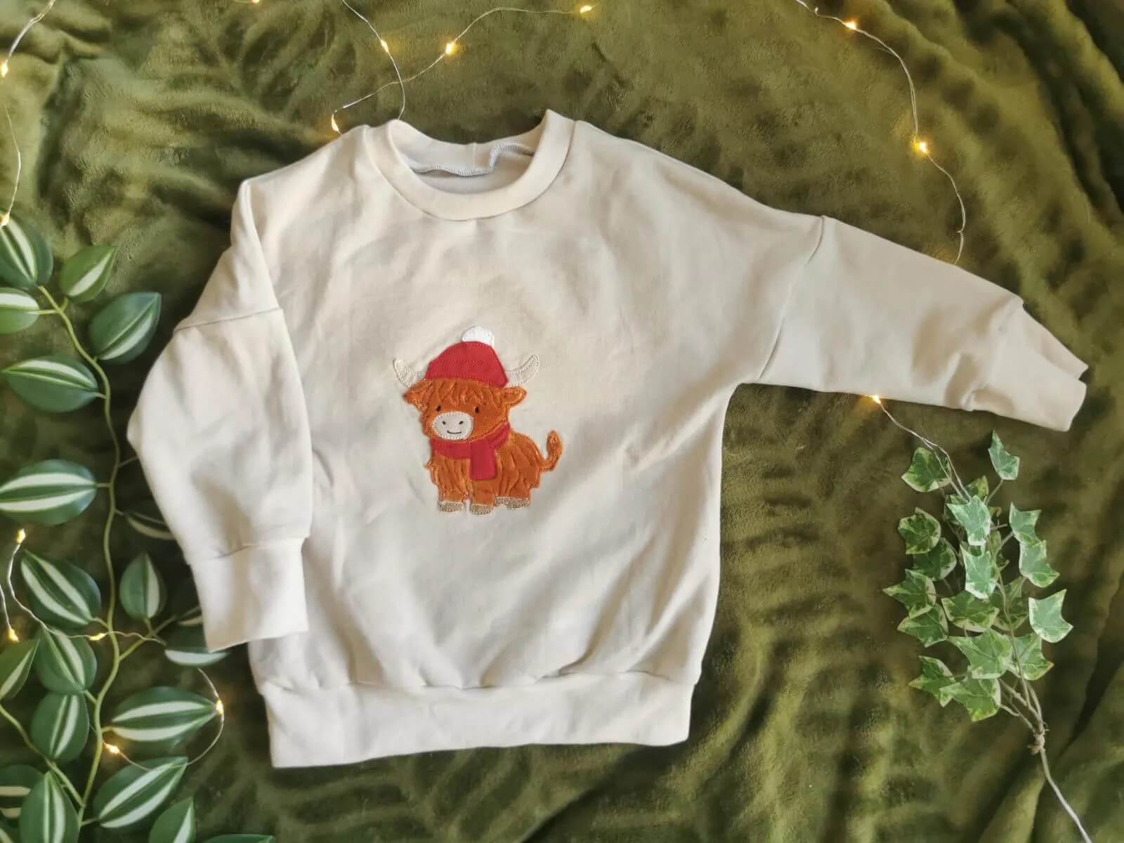 Niedliches Highland Rind mit Mütze – Stickmotiv für Kinderkleidung