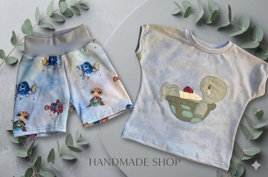 Zeigt das komplette Set aus Shirt und Hose mit maritimem Design.
