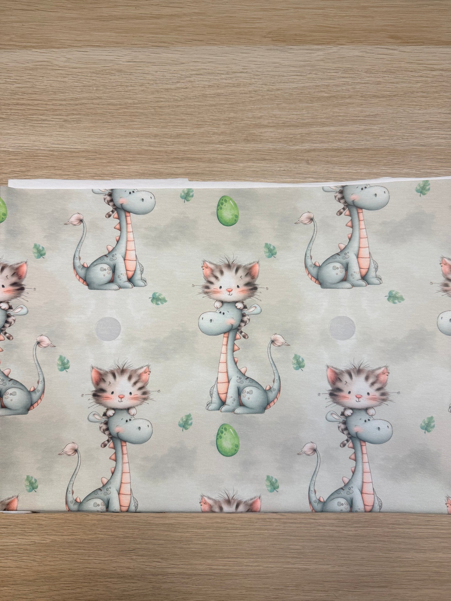 Dino mit Katze Jersey Stoff mit wolkigem Hintergrund und grünen Eiern