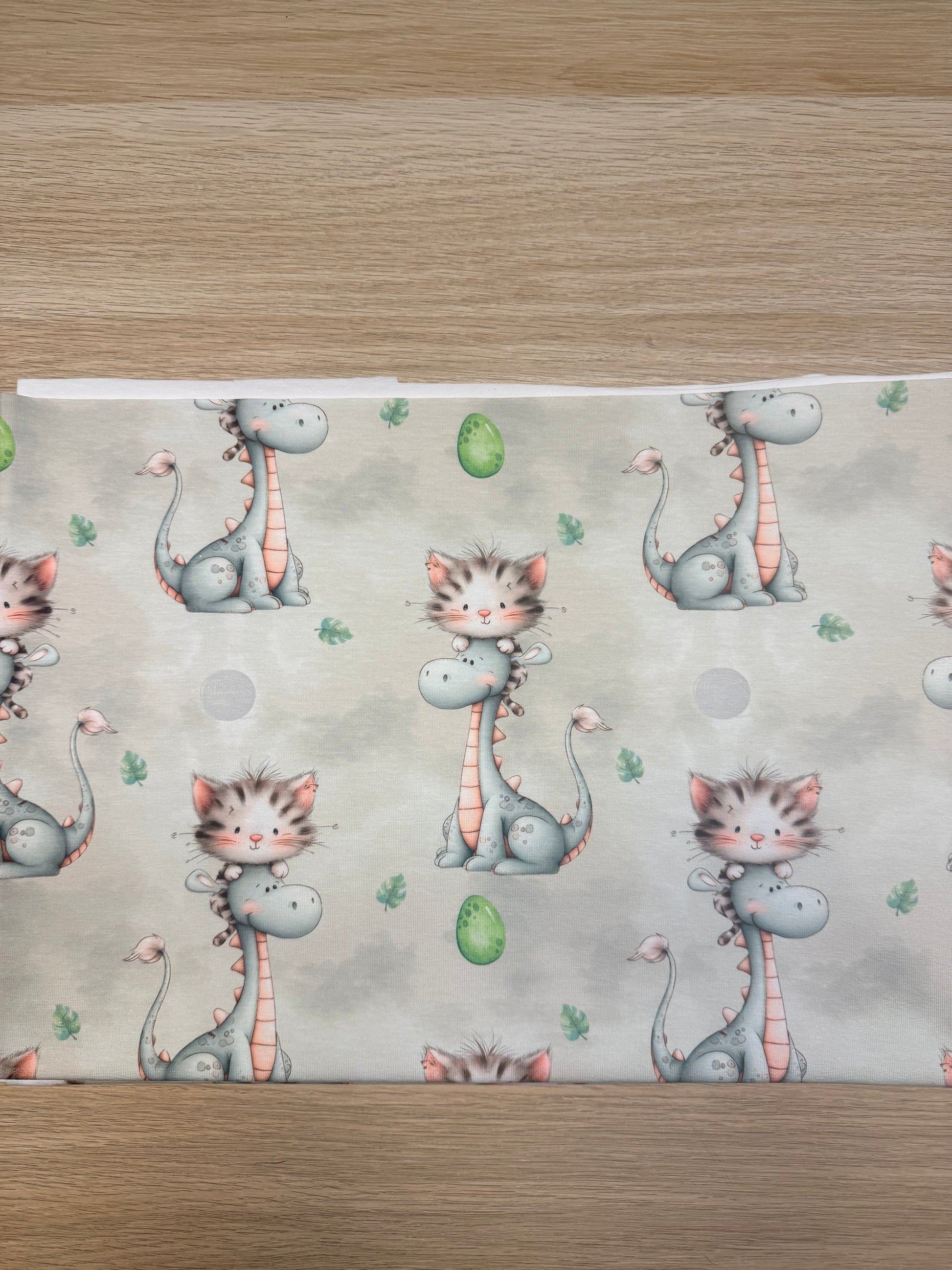 Dino mit Katze Jersey Stoff mit wolkigem Hintergrund und grünen Eiern
