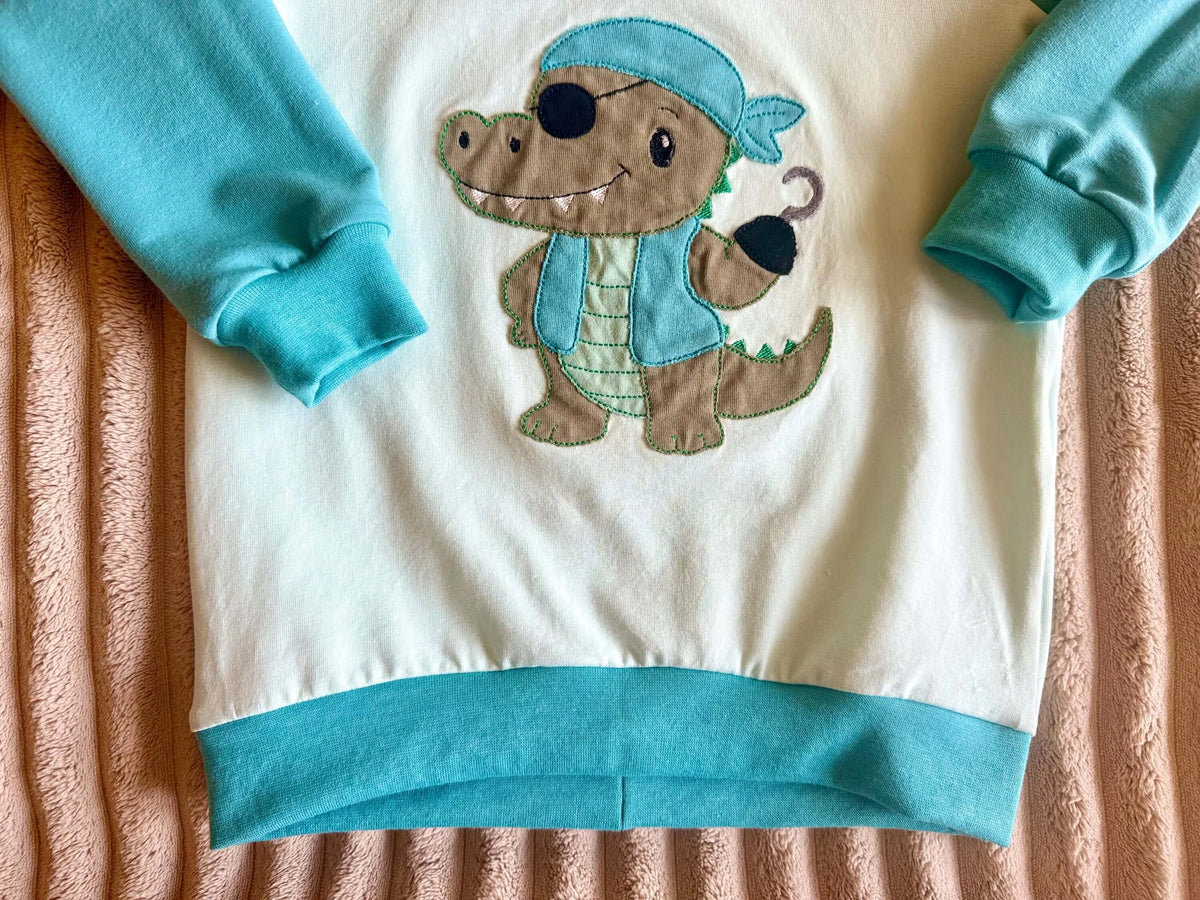 Detailansicht türkises Saumbündchen am Pullover Pirat Kroko Gr. 98