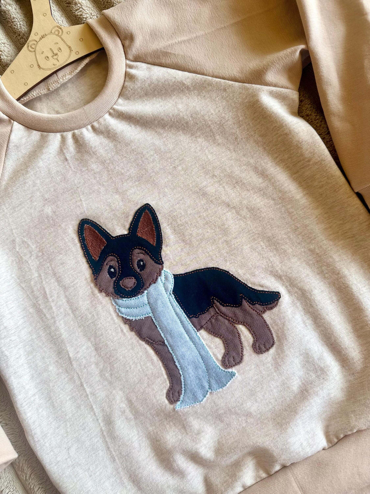 Nahaufnahme Stickapplikation Schäferhund mit Schal auf beigem Jersey Pullover Gr. 98