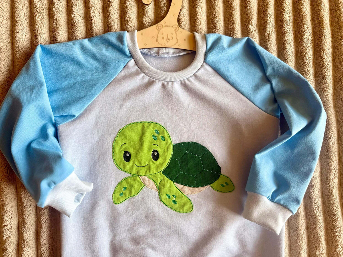 Pullover Kinder Größe 98 blau mit Schildkröten-Motiv, am Kleiderbügel fotografiert