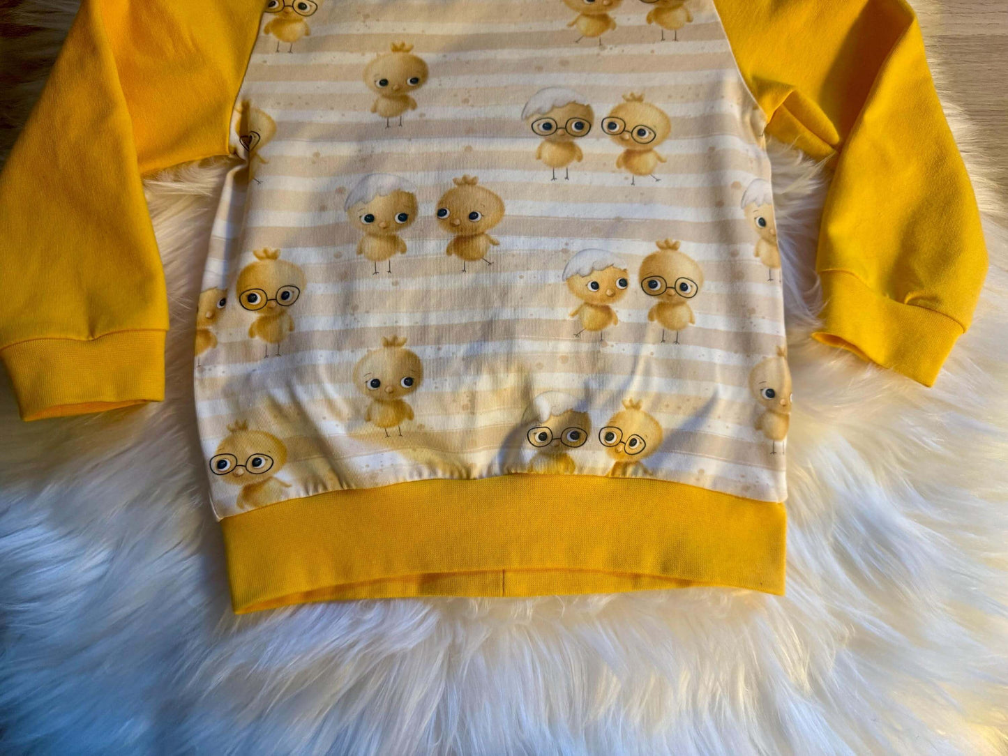 Detailaufnahme des Kükenstoffmusters auf dem Pullover

